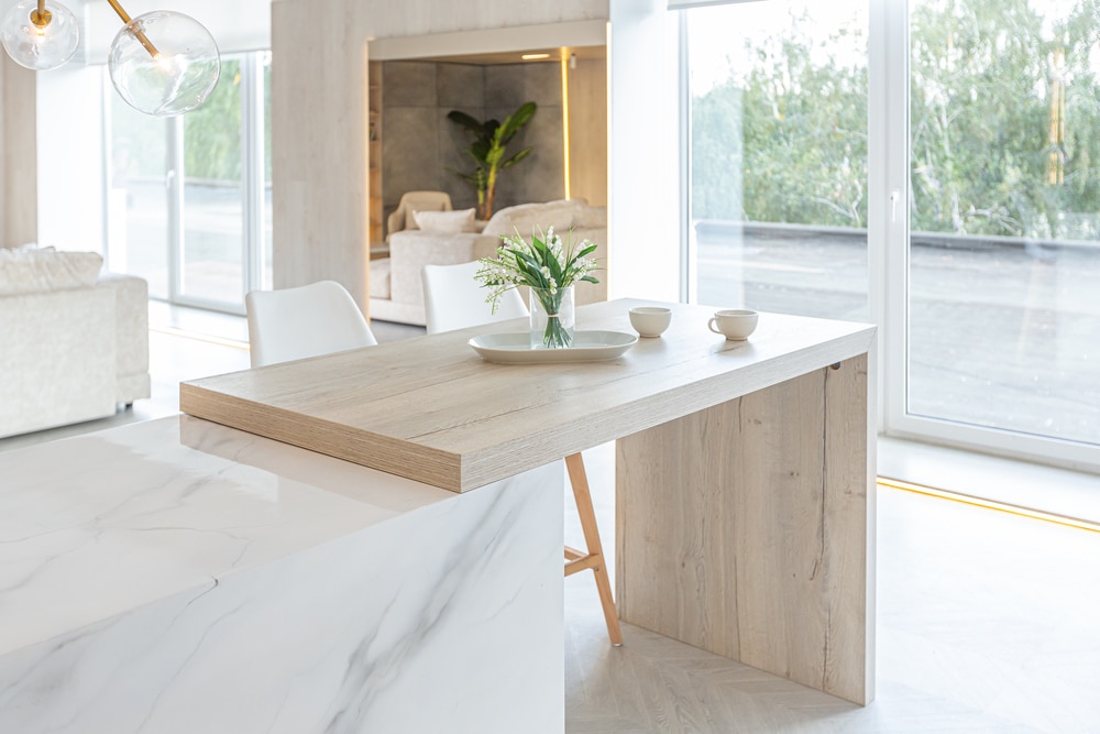 ilot central en marbre avec table intégrée en bois et chaises blanches et bois