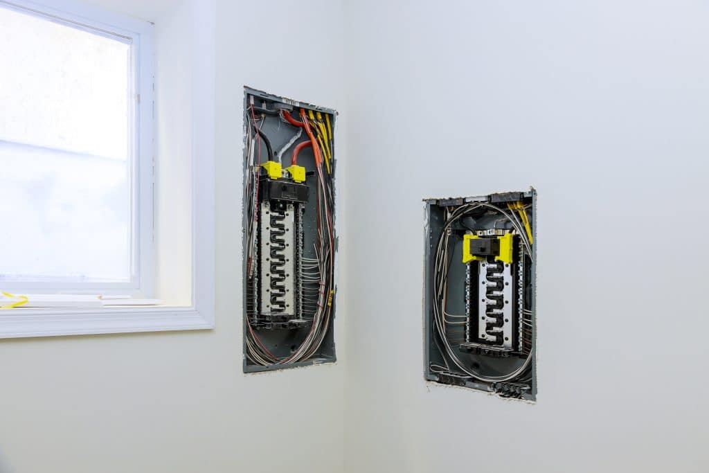 deux boites de fusibles de fils electriques sur un mur blanc