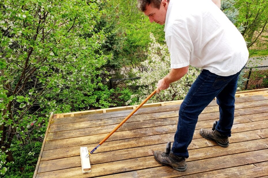 Homme nettoyant sa terrasse en bois